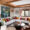 Salon contemporain dans un chalet traditionnel en vieux bois à Courchevel. Le canapé beige est réhaussé de coussin de tissus colorés. Un grand tableau ajoute à l'ambiance chaleureuse du salon réalisé par notre agence d'architecture d'intérieur haut-de-gamme.